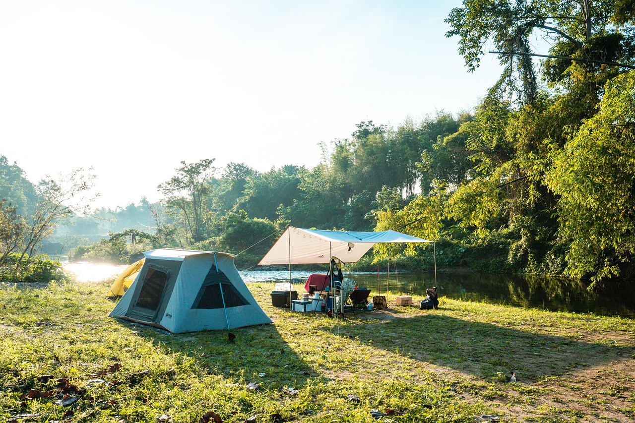 Family campground with tents and RVs under tall trees